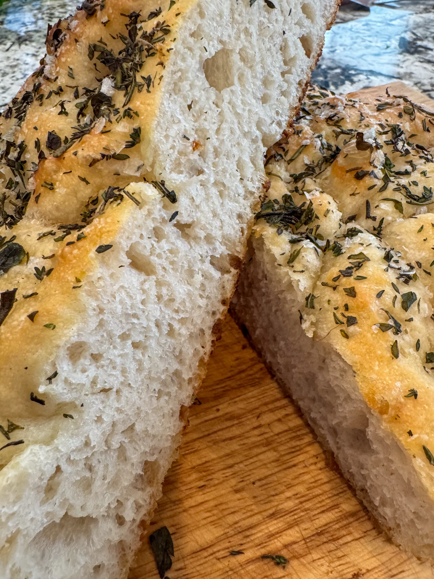 Long-fermented sourdough focaccia with flaky sea salt and rosemary, on a dark wooden board